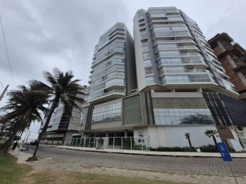Fachada do edifício residencial de vários andares com varandas e estrutura moderna em tom cinza.