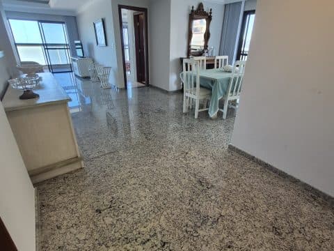 Sala ampla com piso em granito, aparador lateral e acesso a corredor e quartos.